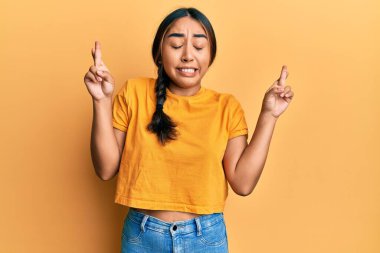 Gündelik kıyafetler giyen genç Latin kadın umut ve gözlerin kapalı gülümseyerek el sallıyor. Şans ve batıl inançlar. 