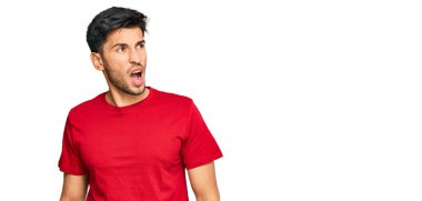 Genç, yakışıklı bir adam, günlük kırmızı tişört giyiyor kızgın ve deli gibi bağırıyor sinirli ve öfkeli, öfkeyle bağırıyor. öfke ve agresif konsept. 