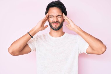 Yakışıklı, beyaz tişört giyen, baş ağrısı çeken, çaresiz ve stresli bir adam. Çünkü acı ve migren ağrısı var. Eller başının üstünde.. 