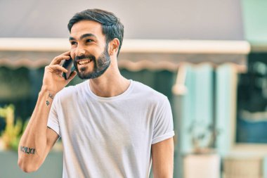 Genç İspanyol adam gülümsüyor. Şehirdeki akıllı telefondan konuşuyor..