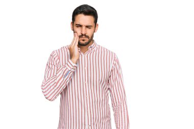 İş gömleği giyen genç İspanyol bir adam diş ağrısı ya da diş hastalığından dolayı acı dolu bir ifadeyle ağıza dokunuyor. dişçi 