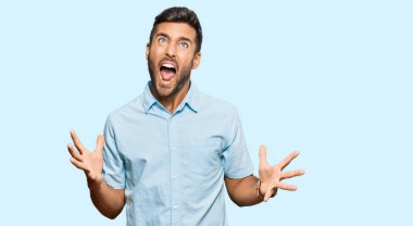 Yakışıklı, sıradan kıyafetler giyen deli deli deli bağıran, agresif bir ifade ve kollarla bağıran bir İspanyol. hüsran kavramı. 