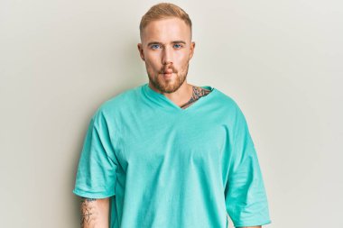 Günlük kıyafetler giyen genç beyaz bir adam dudaklarıyla balık suratı yapıyor, çılgınca ve komik bir jest. Komik ifade. 