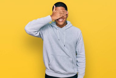 Genç, yakışıklı, sıradan bir kazak giyen, gülümseyen ve elleri yüzünde, şaşırtmak için gözlerini kapatan İspanyol bir adam. kör kavram. 