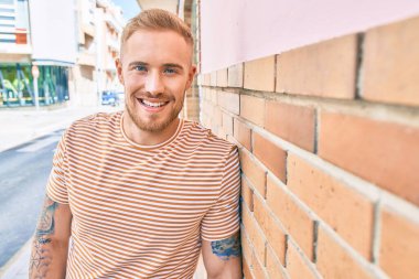 Genç İrlandalı gülümseyen mutlu adam şehrin duvarına yaslanıyor..