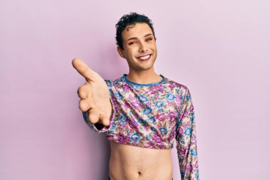 Moda kıyafetleri giymiş yakışıklı bir adam gülümseyerek selamlaşma ve dostça tokalaşma sunuyor. başarılı iş. 