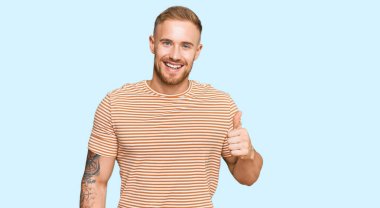 Genç İrlandalı günlük kıyafetler giyen mutlu ve pozitif gülümseyen, mükemmel ve onay işareti yapan bir adam. 