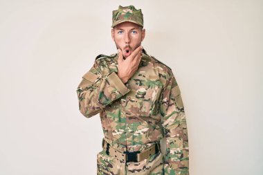 Kafkasyalı genç adam kamuflaj üniforması giyiyor. İnançsızlıktan, şaşkınlıktan ve elleri çenesinde şaşkınlıktan büyülenmiş görünüyor. 