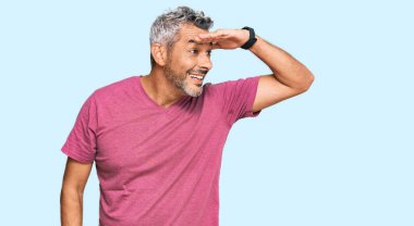 Orta yaşlı, gri saçlı, günlük kıyafetler giyen mutlu ve tebessüm eden bir adam. arama kavramı. 