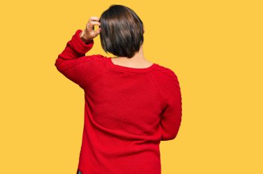 Kısa saçlı, sıradan süveter giyen ve gözlüklü genç ve güzel bir İspanyol kadın. Elleri başının üstünde şüpheyi düşünüyor. 