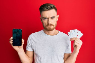 Genç kızıl saçlı adam elinde akıllı telefon ve kumarhane kartı tutuyordu. Depresyondaydı ve üzüntüden ağlıyordu. Kızgın ve korkmuştu. hüzünlü ifade. 