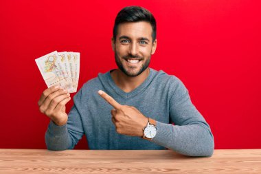 Birleşik Krallık 'ı elinde tutan yakışıklı İspanyol adam mutlu bir şekilde elini ve parmağını gösterdi. 