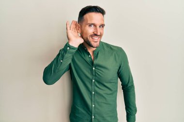 Sakallı, sıradan kıyafetler giyen, kulağı kulağında gülümseyen dedikoduları ve dedikoduları dinleyen yakışıklı bir adam. Sağırlık kavramı. 