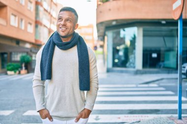 Genç beyaz adam gülümseyerek şehirde mutlu mesut yürüyor..