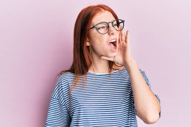 Genç kızıl saçlı kız, gündelik kıyafetler ve gözlük takıp el ele tutuşarak bağırıyor ve çığlık atıyordu. iletişim konsepti. 