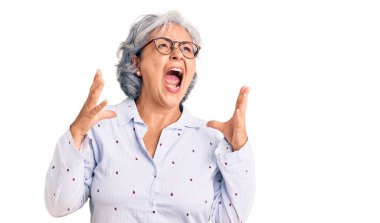 Gri saçlı, sıradan iş kıyafetleri giyen, gözlüklü, deli deli deli bağıran, agresif ifade ve kollarıyla bağıran son sınıf öğrencisi kadın. hüsran kavramı. 