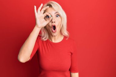 Sıradan kıyafetler giyen genç sarışın kız şaşırmış yüz ifadesiyle şok olmuş, parmaklarından bakan gözler. İnançsız ifade. 