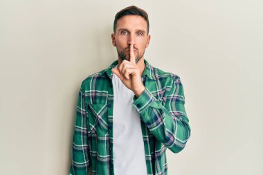 Sakallı, sıradan kıyafetler giyen, dudakları parmaklarıyla sessiz olmak isteyen yakışıklı bir adam. sessizlik ve gizli konsept. 