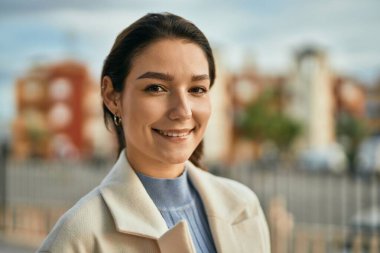 Genç İspanyol kadın gülümseyerek şehirde mutlu mesut dikiliyor.