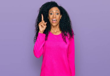 Orta yaşlı Afro-Amerikan kadın gündelik giysiler giyip başarılı bir fikri işaret ediyor. Heyecanlı ve mutlu. Bir numara.. 