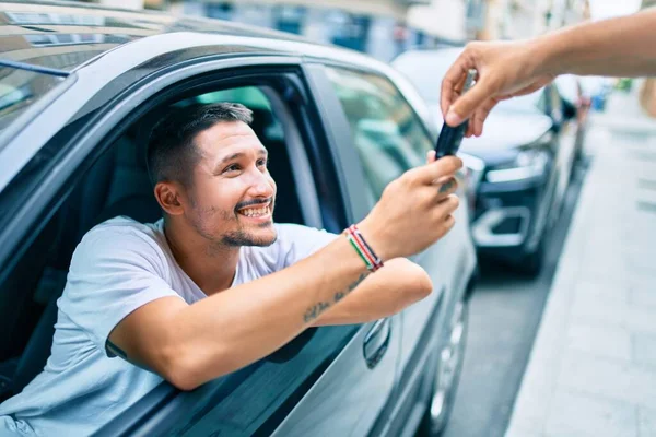 Yeni arabanın anahtarını tutarken mutlu gülümseyen İspanyol genç adam.