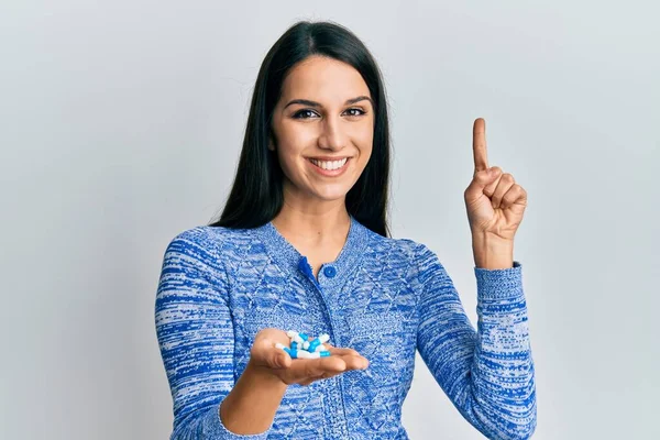 Jovem Hispânica Segurando Pílulas Sorrindo Com Uma Ideia Pergunta Apontando — Fotografia de Stock