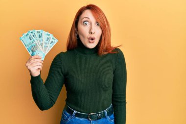 Güzel kızıl saçlı kadın 50 Hintli banknot tutuyor. Şaşırtıcı bir şekilde korkmuş ve hayrete düşmüştü. İnanmayan yüz. 