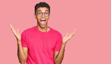 Genç, yakışıklı, Afro-Amerikalı, günlük kıyafetler giymiş mutlu bir gülümsemeyle zaferi kutluyor ve ellerini kaldırarak kazanan bir ifade sergiliyor. 