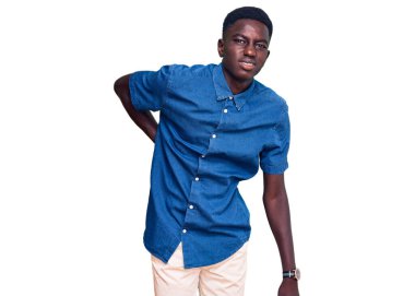 Genç Afro-Amerikan adam gündelik kıyafetler giyiyor sırt ağrısı çekiyor, elleriyle dokunuyor, kas ağrısı çekiyor. 