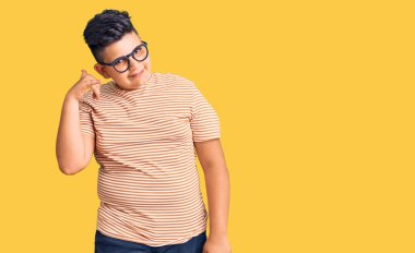 Küçük çocuk günlük kıyafetler ve gözlük takıyor gülümsüyor telefonla el ve parmaklarıyla jest yapıyor telefonda konuşuyor gibi. iletişim kavramları. 