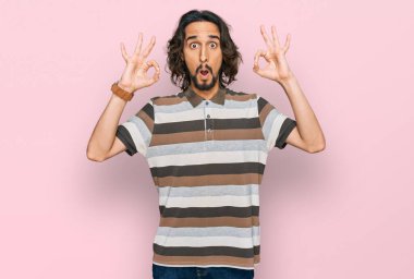 Gündelik kıyafetler giyen genç İspanyol adam şaşırmış ve şok olmuş görünüyor. Tamam sembolünü parmaklarıyla yapıyor. çılgın ifade 