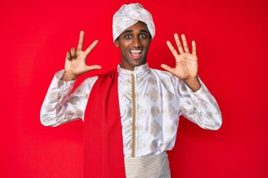 Sherwani sari giysisi giyen yakışıklı Hintli adam 8 numaralı parmaklarıyla kendini beğenmiş ve mutlu gülümserken kendini gösteriyor.. 