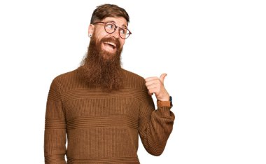 Genç İrlandalı kızıl elbiseli ve gözlüklü mutlu yüzlü gülümseyen ve baş parmağıyla yan tarafı gösteren adam.. 