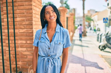 Genç Afrikalı Amerikalı kadın gülümseyerek şehirde mutlu mesut yürüyor..