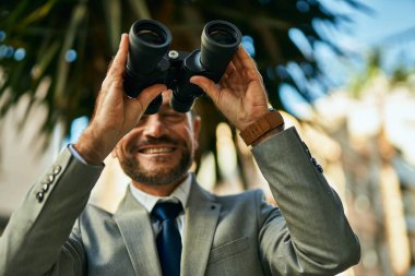 Orta yaşlı işadamı şehirde dürbünle yeni fırsatlar arıyor..