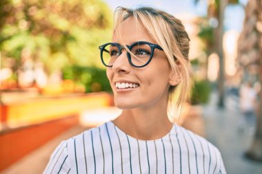 Genç sarışın iş kadını gülümseyerek şehirde mutlu mesut yürüyor..