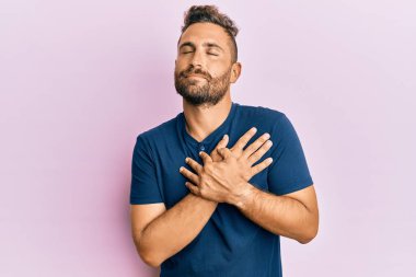 Sakallı, sıradan kıyafetler giyen, elleri göğsünde, gözleri kapalı, yüzünde minnet ifadesi olan yakışıklı bir adam. sağlık kavramı. 