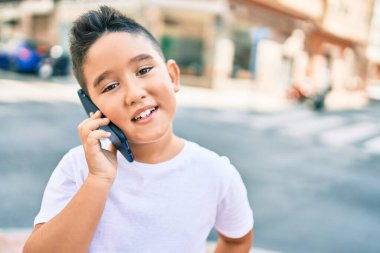 Sevimli çocuk gülümsüyor. Şehrin caddesinde akıllı telefondan konuşuyor..