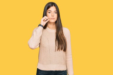 Kış süveteri giyen genç esmer kadın ağzı ve dudakları parmaklarıyla fermuar gibi kapalı. gizli ve sessiz, tabu konuşması 