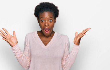 Genç Afro-Amerikan kızı sıradan kıyafetler giyip çılgınlığı kutluyor ve başarıyı kolları açık ve gözleri açık heyecanla haykırarak kutluyor. Kazanan konsept 