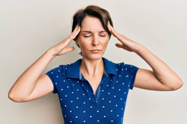 Kısa saçlı, elleri kafasında, günlük kıyafetler giyen esmer bir kadın. Stres yüzünden baş ağrısı çekiyor. migren ağrısı. 