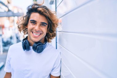 Şehrin duvarına dayanmış, kulaklık takan yakışıklı İspanyol bir adam.