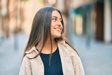 Genç İspanyol kız gülümseyerek şehirde mutlu mesut dikiliyor..