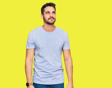 Gündelik kıyafetler giyen genç İspanyol adam gülümseyip yan tarafa bakıyor ve düşünüyor.. 