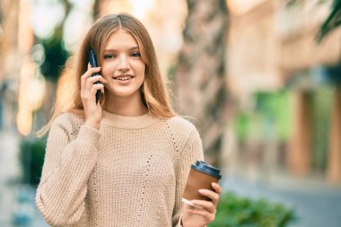 Kafkasyalı güzel bir genç şehirde kahve içerek akıllı telefondan konuşuyor..