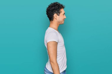 Tişört giyen yakışıklı bir genç. Yan tarafa bakıyor, rahat poz veriyor. Kendine güvenen bir gülümsemesi var.. 