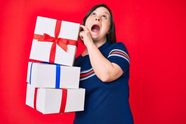 Down sendromlu esmer bir kadın elinde hediyeler, kızgın ve kızgın çığlıklar, sinirli ve öfkeli, öfkeyle bağırıyor. öfke ve agresif konsept. 