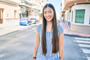 Genç Çinli kadın gülümsüyor. Şehrin caddesinde mutlu bir şekilde yürüyor..