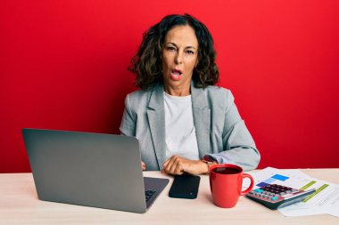 Ofiste çalışan orta yaşlı güzel bir kadın şok olmuş bir şekilde bir fincan kahve içiyor. Şüpheci ve alaycı görünüyor. 