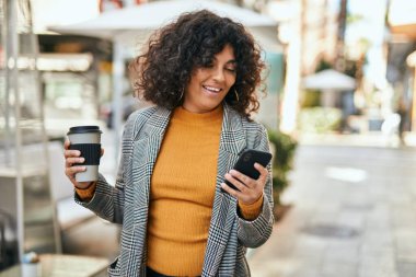 Genç İspanyol iş kadını akıllı telefon kullanıyor. Şehirde kahve içiyor..
